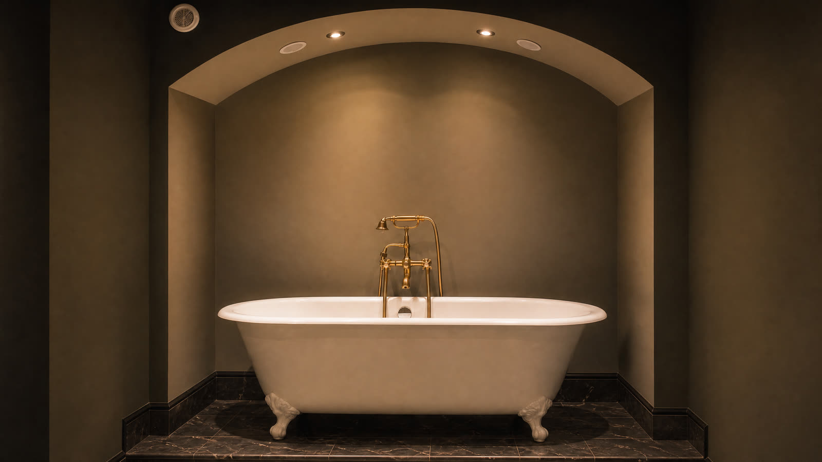 Une baignoire sur pieds dans une alcôve voûtée, en lumière tamisée.