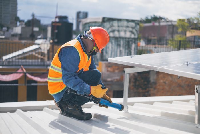 Un ouvrier fixe le support d’un panneau solaire sur un toit