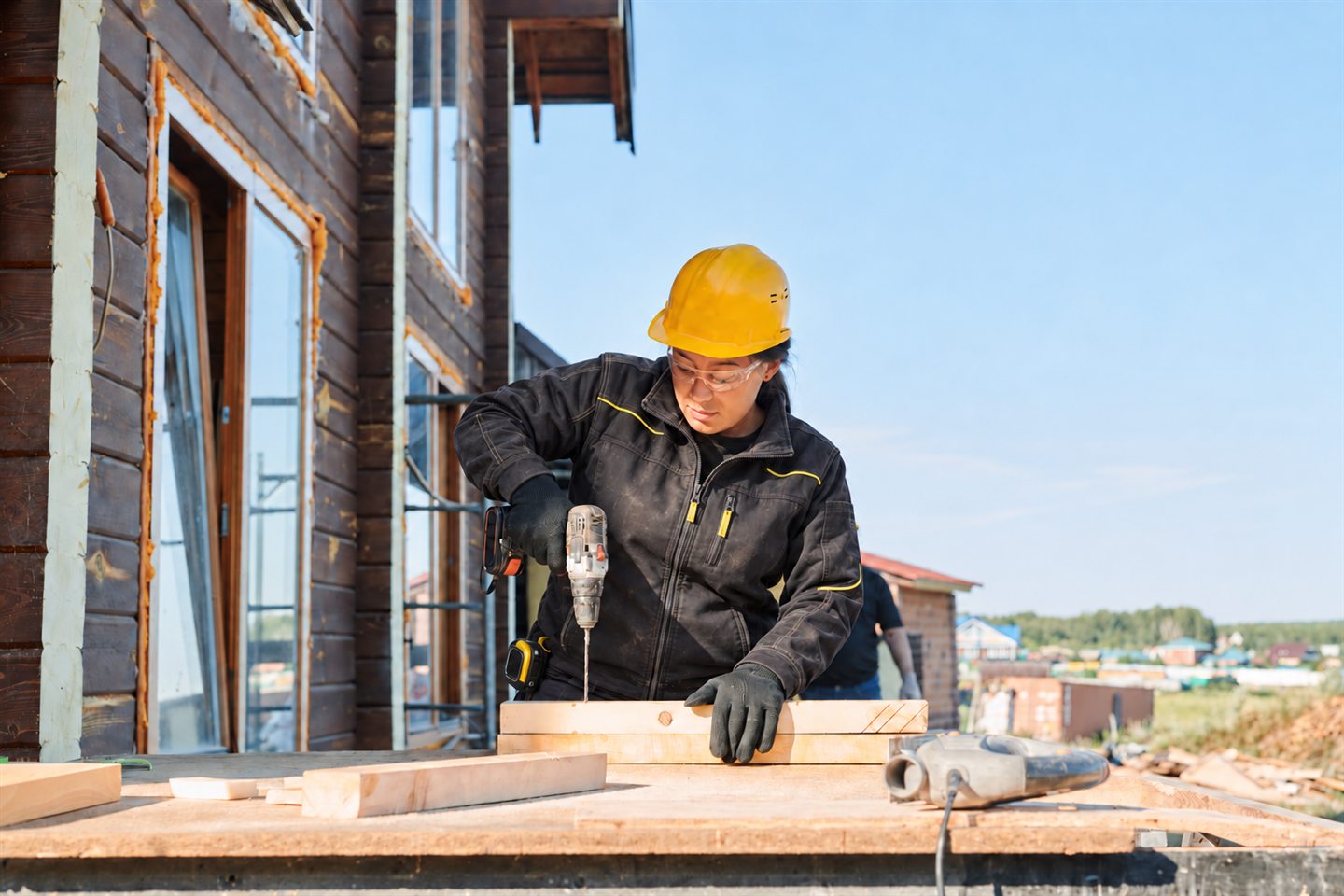 Artisane perçant une pièce de bois sur le chantier d’une maison