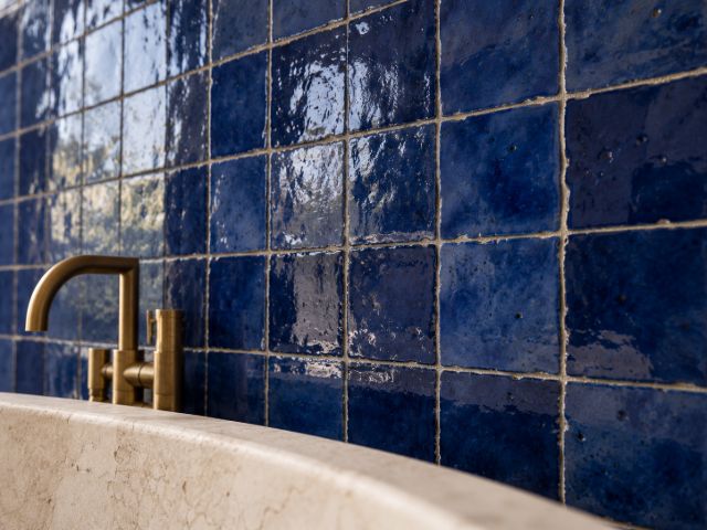 Glazed cobalt zellige behind a brass tap