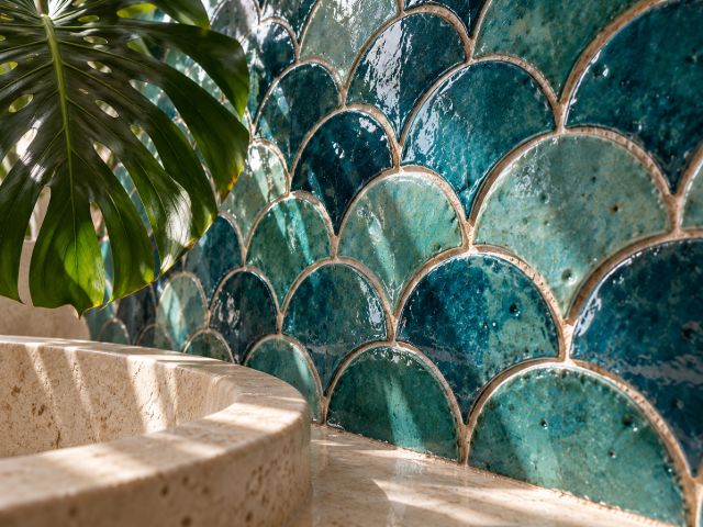 Turquoise fish-scale zellige around a stone tub