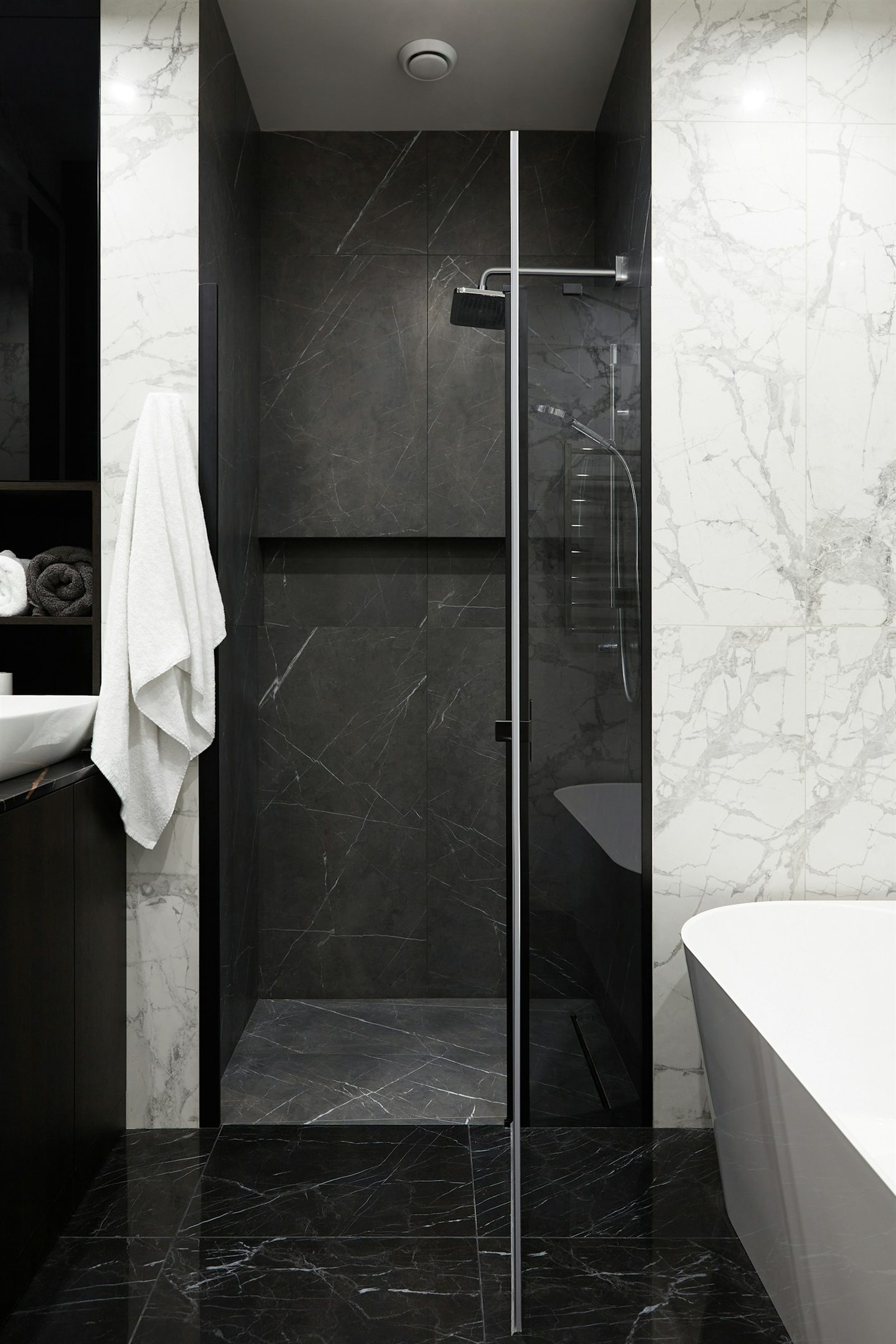 Salle de bain sombre avec douche vitrée et baignoire blanche