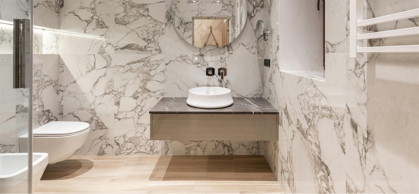 Salle de bain en marbre blanc veiné, vanité suspendue et vasque ronde