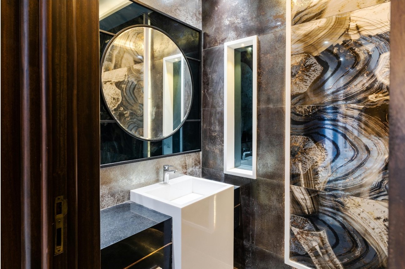 Salle de bain en onyx et marbre, miroir rond et lavabo blanc