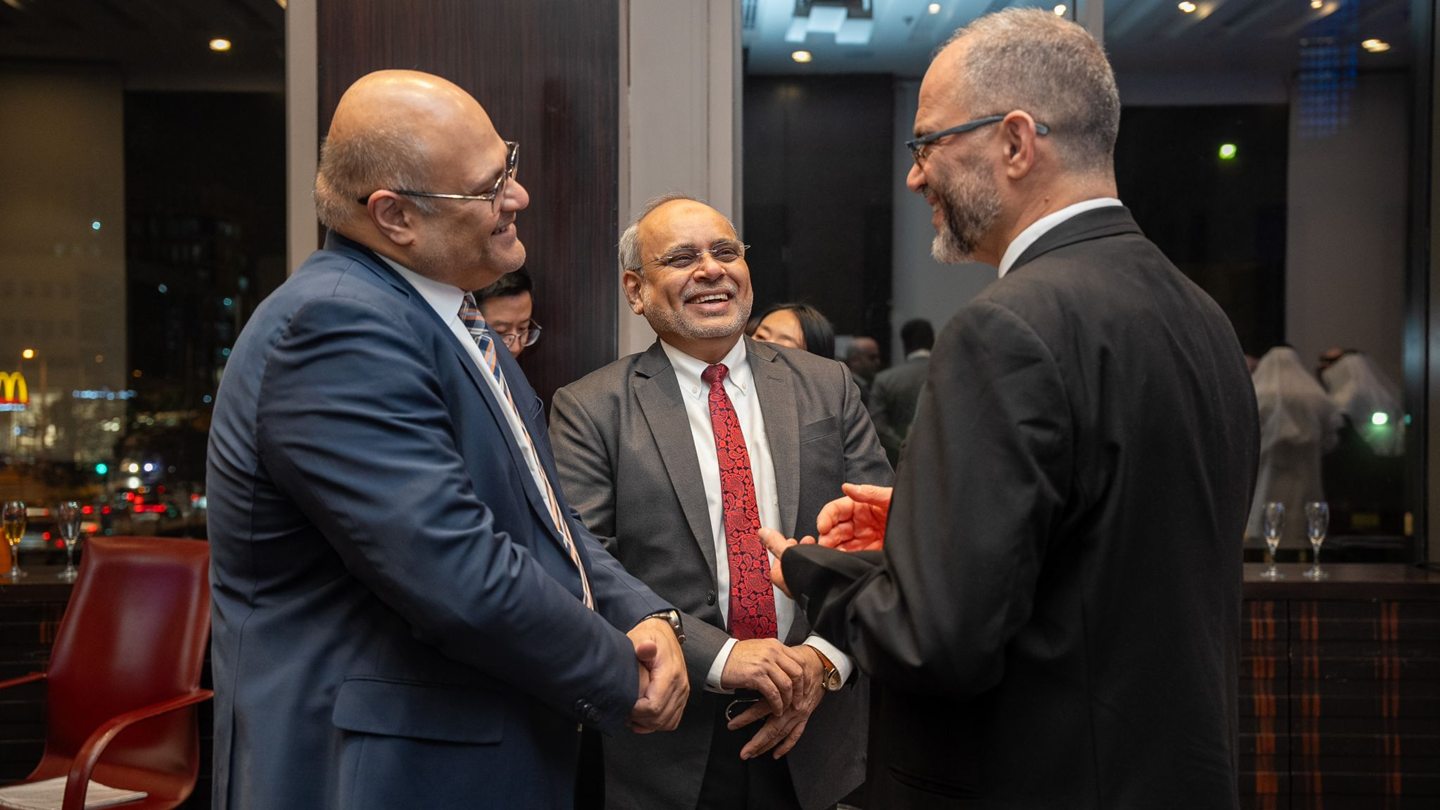 Trois membres du Groupe PBE échangent en souriant lors d’un événement professionnel