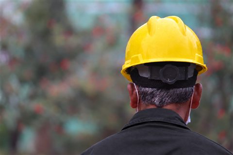 Membre de l’équipe vu de dos, casque jaune