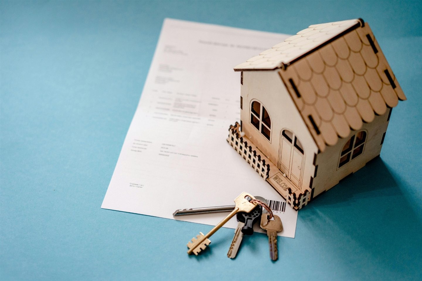Maquette de maison en bois posée sur un document, avec un trousseau de clés