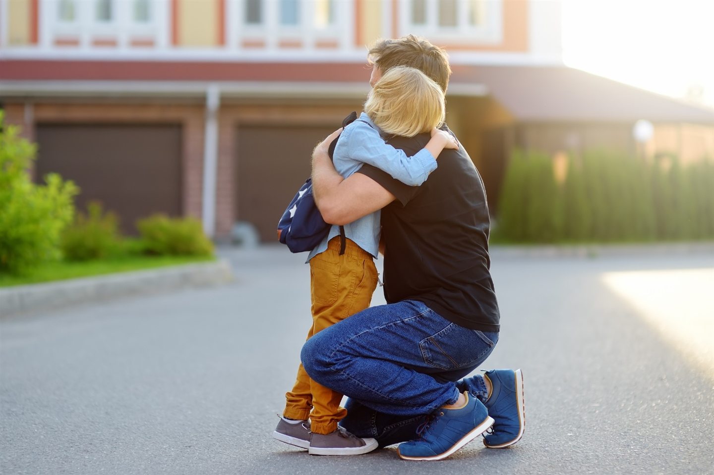 A parent hugging their child in front of a house