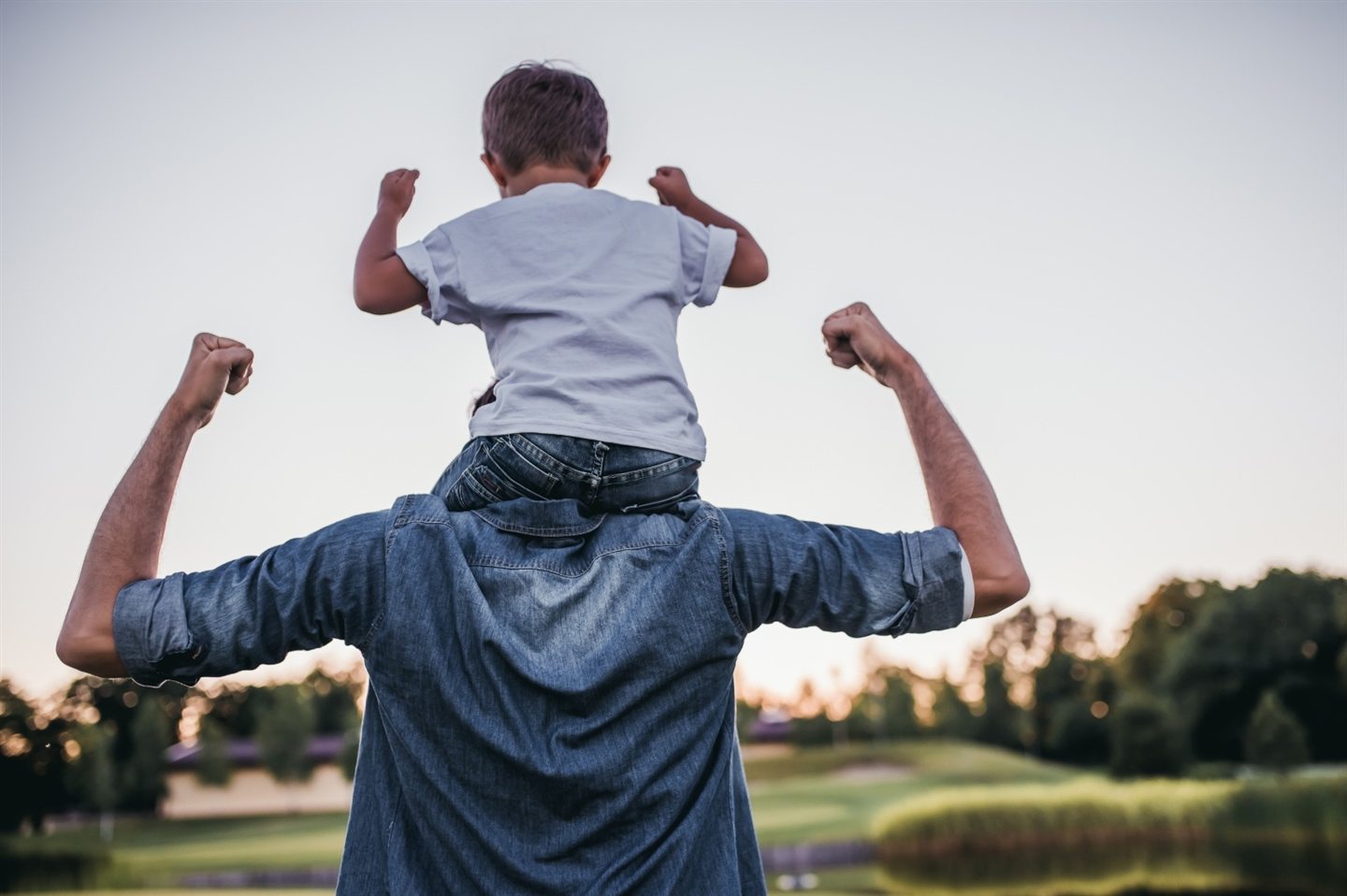 Child on his father’s shoulders, arms raised