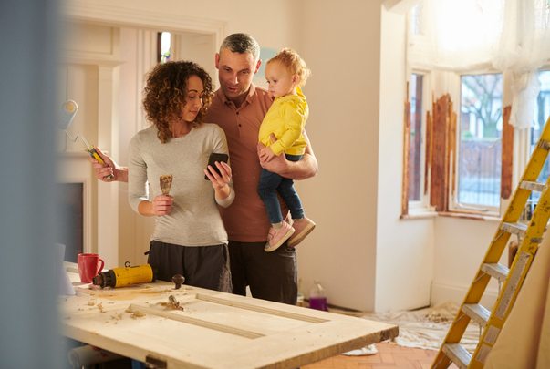 Smiling family in a room being renovated, holding a child