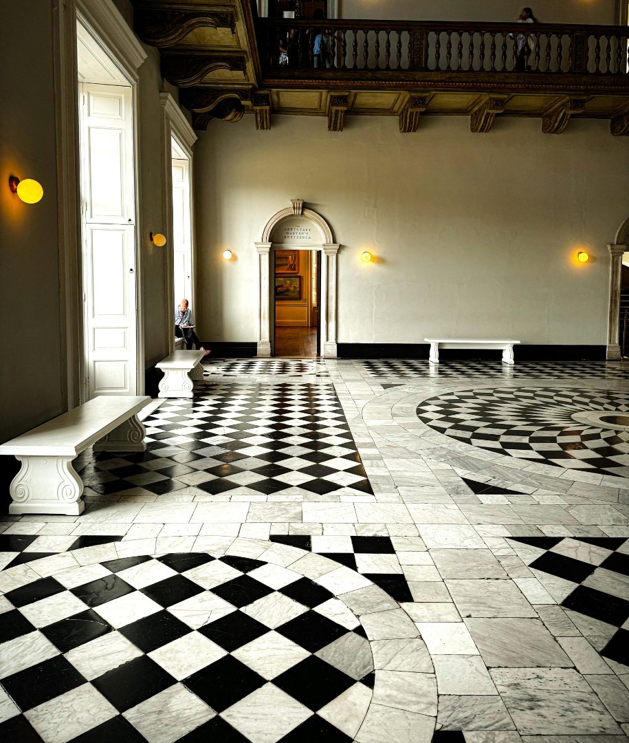 Hall classique au plancher en damier noir et blanc, rosace et banc de pierre