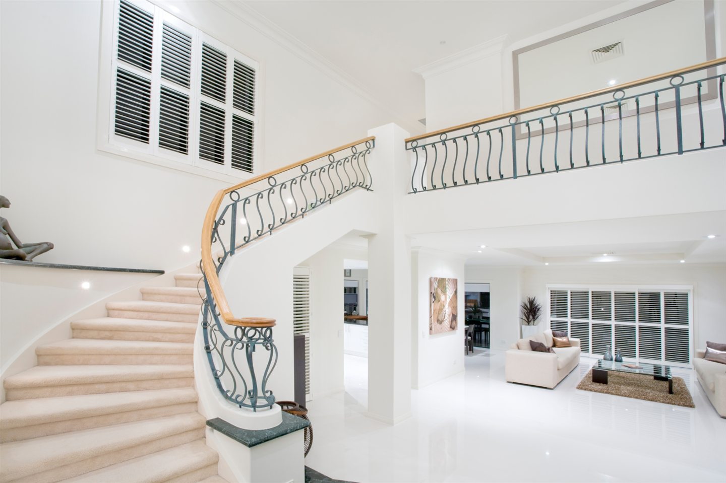 Hall blanc lumineux avec escalier courbe et mezzanine