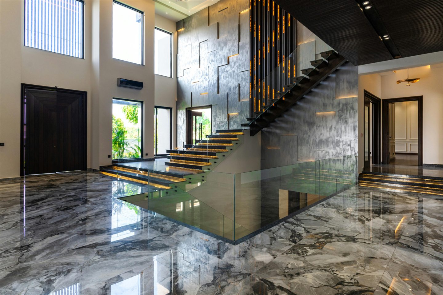 Hall au plancher de marbre et escalier à garde-corps de verre