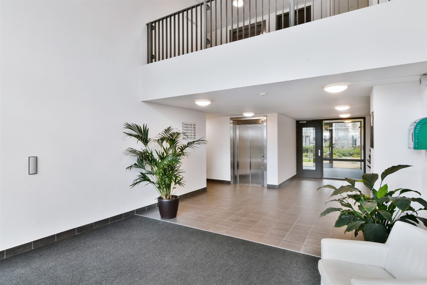 Hall d’entrée blanc sous une mezzanine vitrée