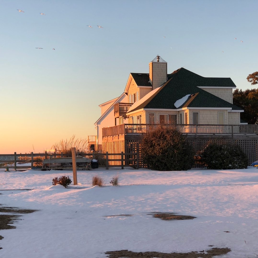 Maison au bord de l’eau en hiver, au coucher du soleil