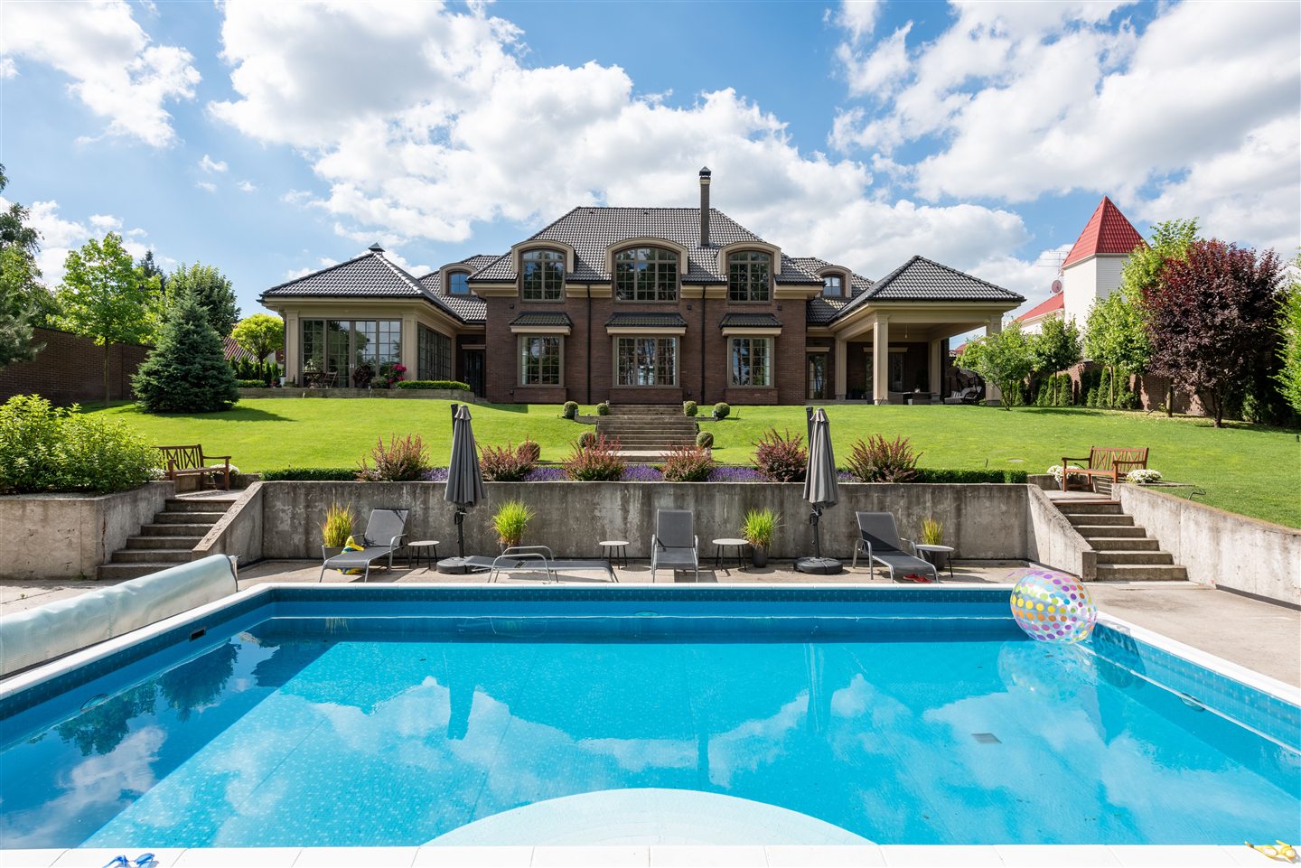 Grande maison entourée d’arbres avec piscine et jardin