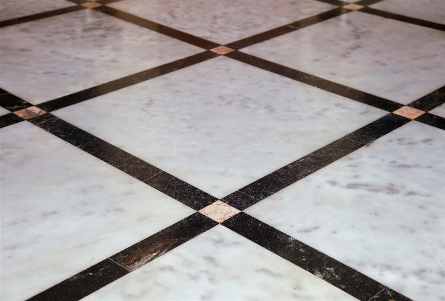 Plancher de marbre blanc bordé de bandes noires et de cabochons roses