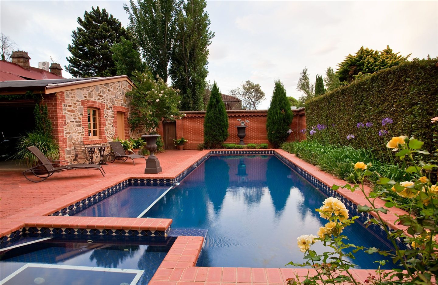 Piscine creusée bordée de brique, dans un jardin fleuri