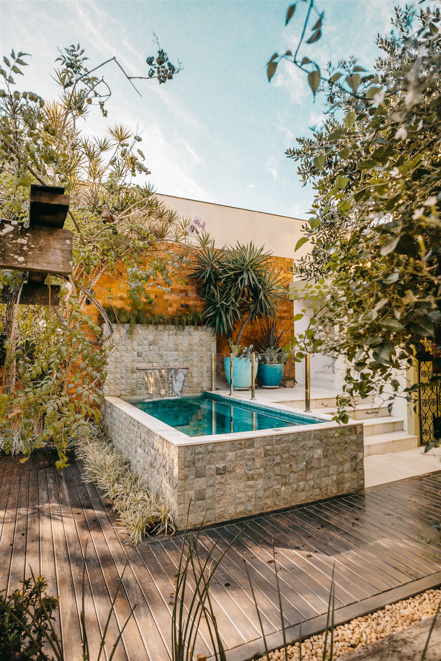 Petite piscine surélevée en pierre, entourée de plantes