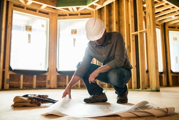 Site supervisor reading plans on the floor, inside a wood frame