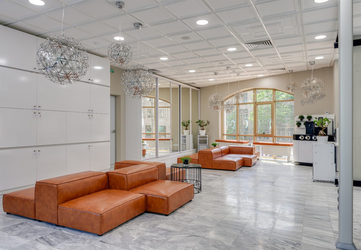 Grand espace lumineux aux canapés de cuir cognac et suspensions de verre
