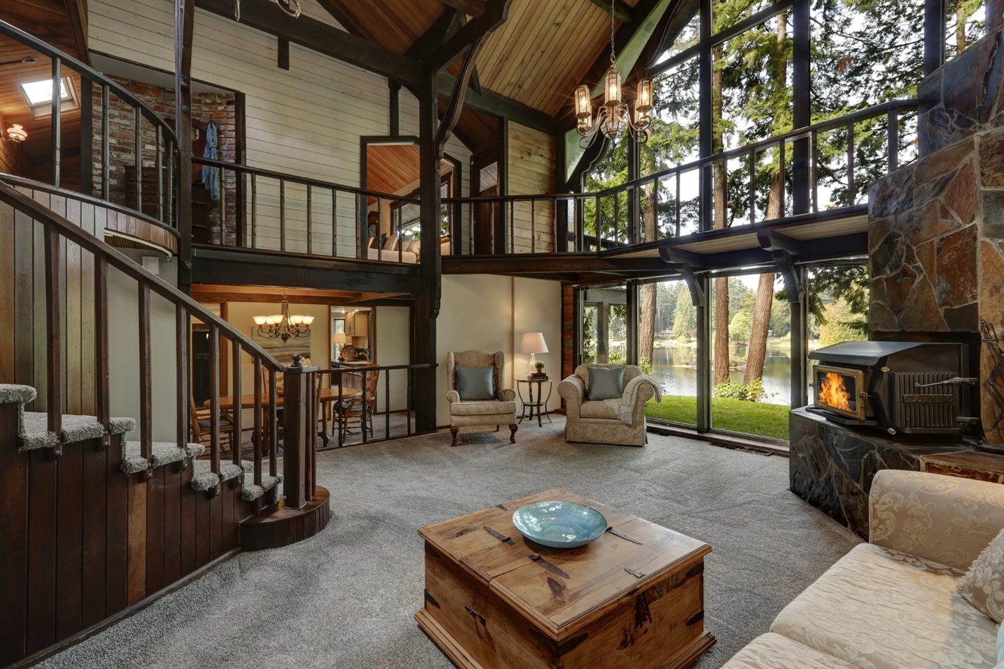 Living room with a mezzanine, metal staircase and wood stove