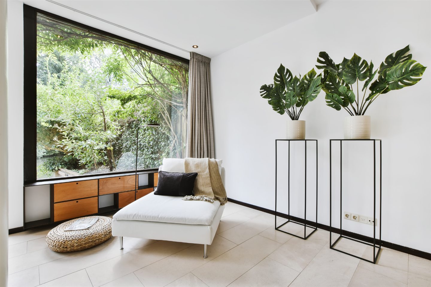 White relaxation corner in front of a large picture window onto greenery