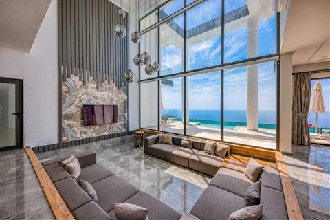 Salon encastré sous une grande verrière avec vue sur la mer