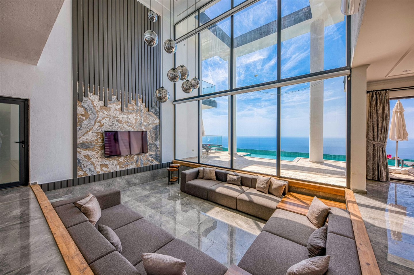 Salon encastré sous une grande verrière avec vue sur la mer
