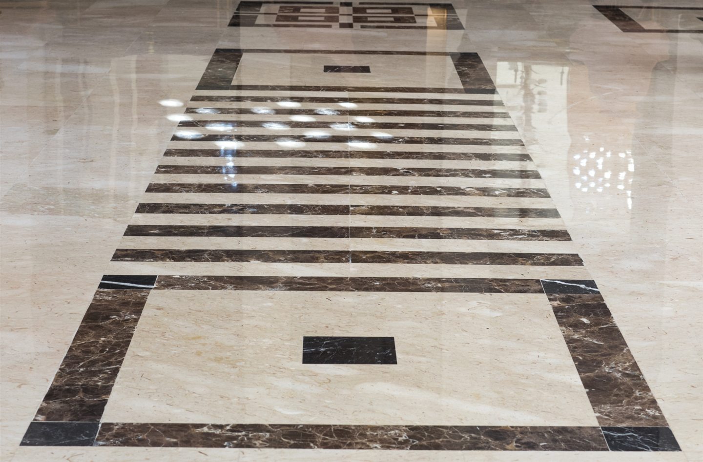 Motif de marbre crème et brun incrusté dans un plancher poli
