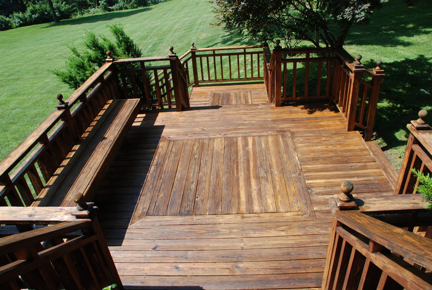 Grande terrasse de bois teint avec garde-corps, ouverte sur la pelouse