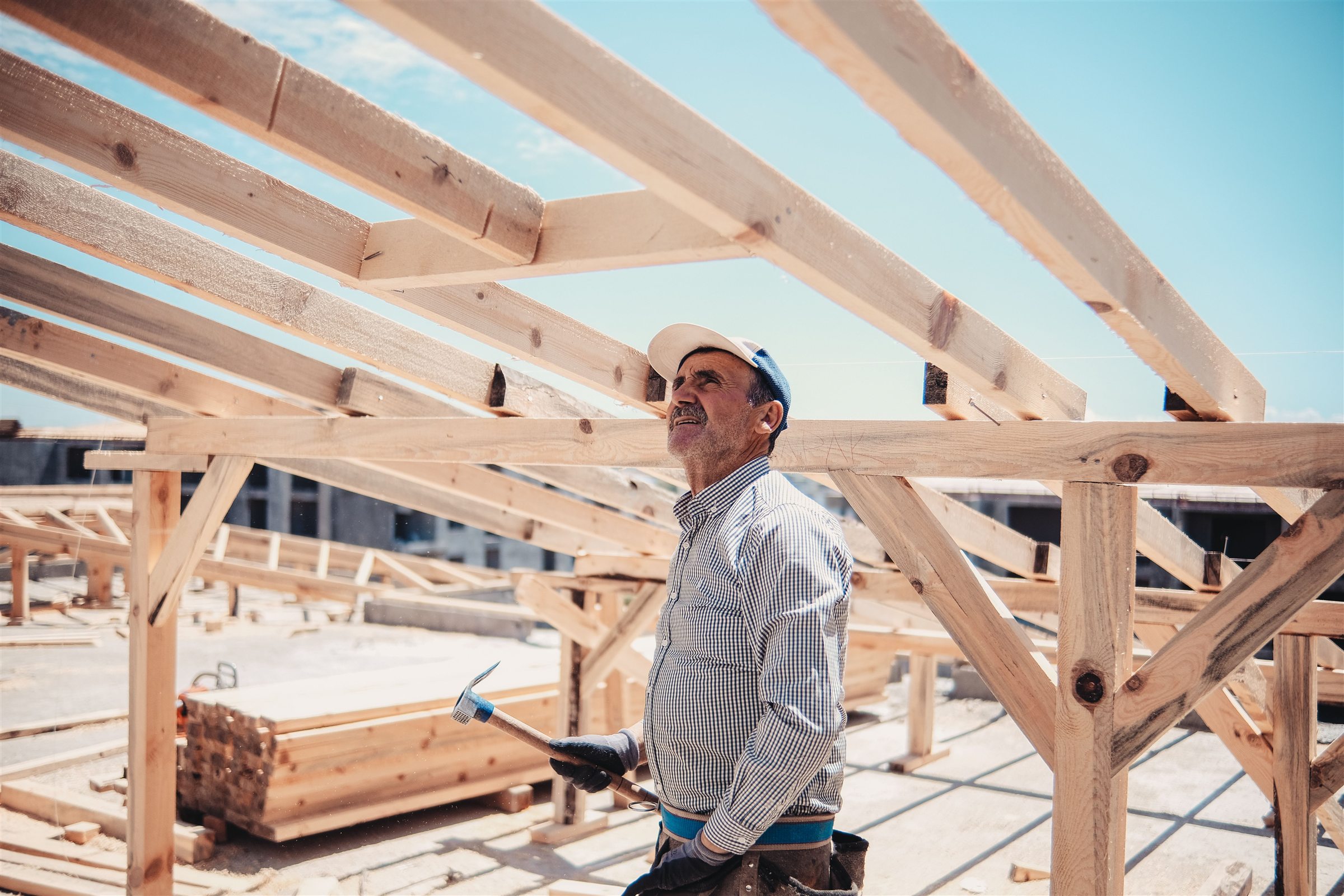 Carpenter looking at the wooden roof framing of a house under construction