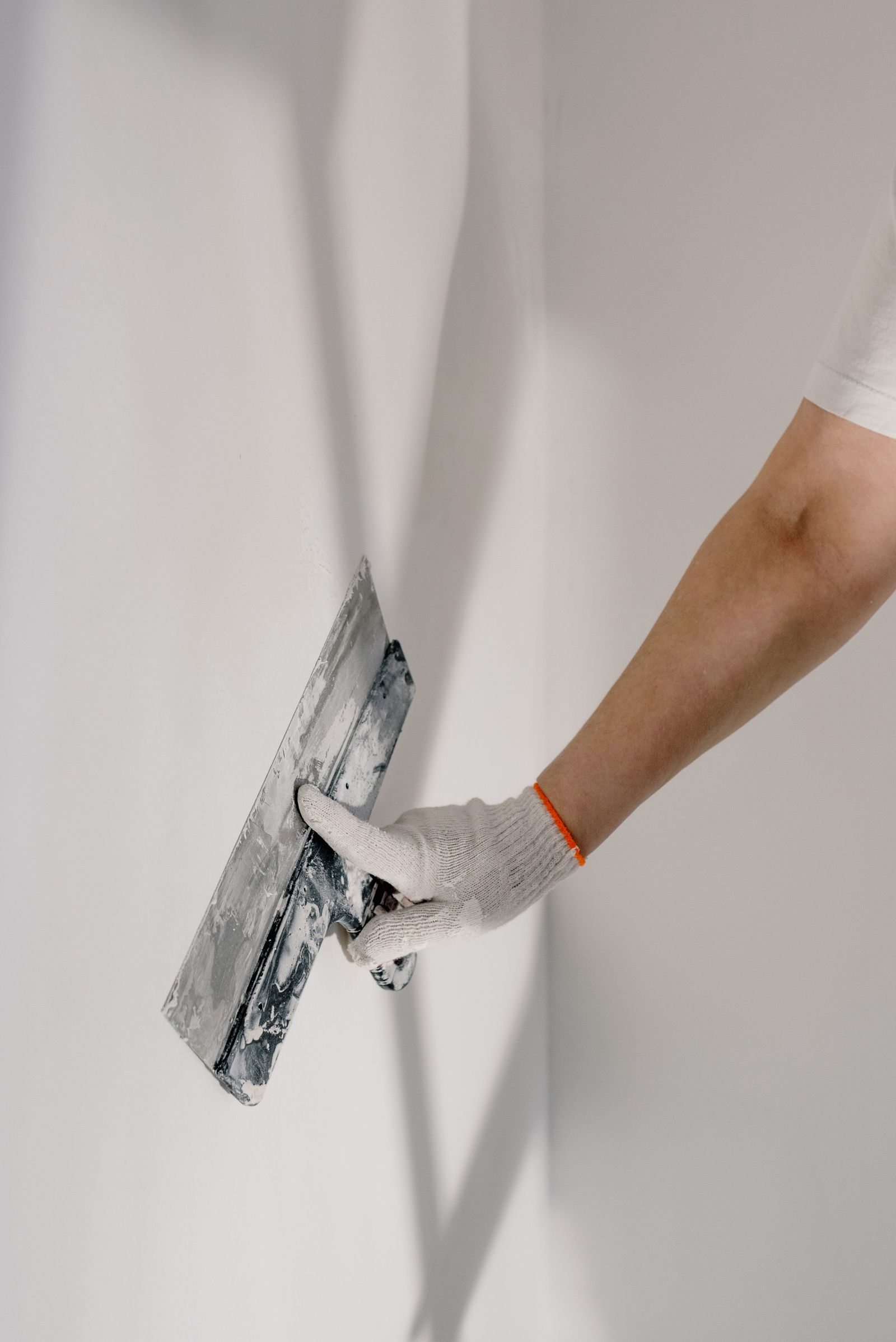 Main d’un professionnel appliquant de l’enduit sur un mur