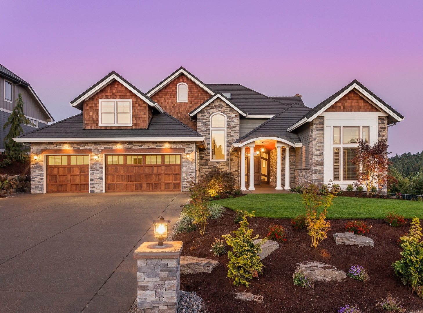 House lit at dusk with a landscaped garden