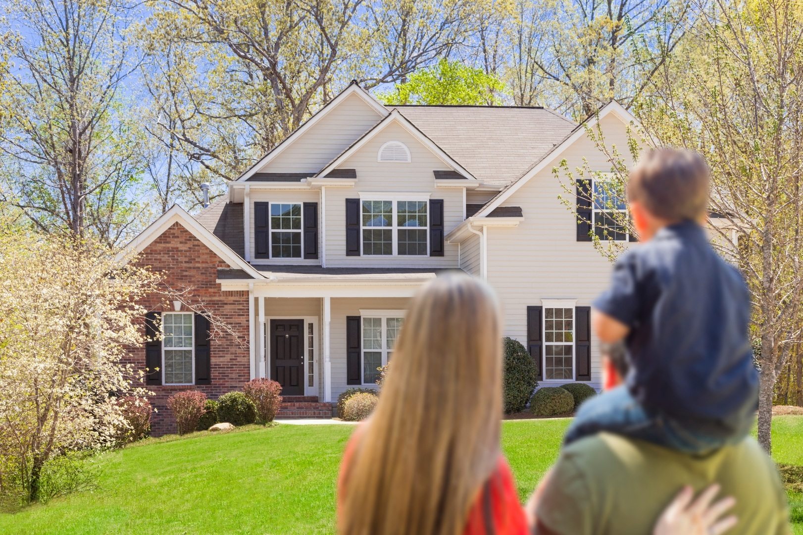 Family in front of a house surrounded by spring trees
